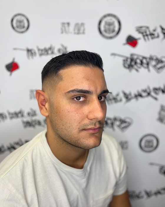 Slick back με fade, μπροστά στον τοίχο του μαγαζιού