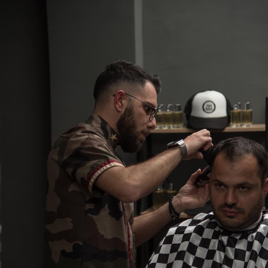 Ο Αλέξανδρος κουρεύει έναν πελάτη με καρό κάπα